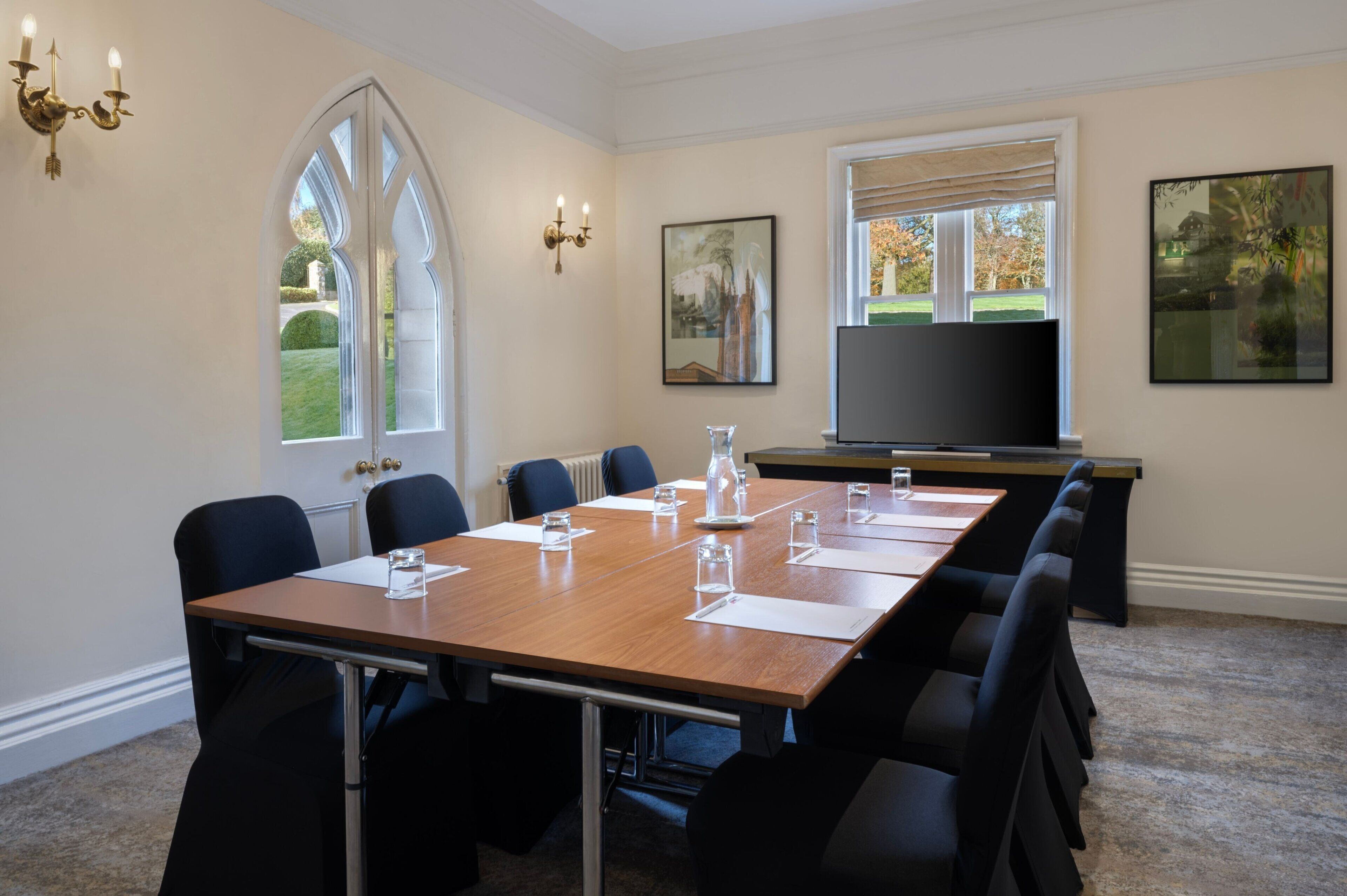 Une salle de conférence avec une longue table, des chaises, un téléviseur et des œuvres d’art accrochées aux murs.