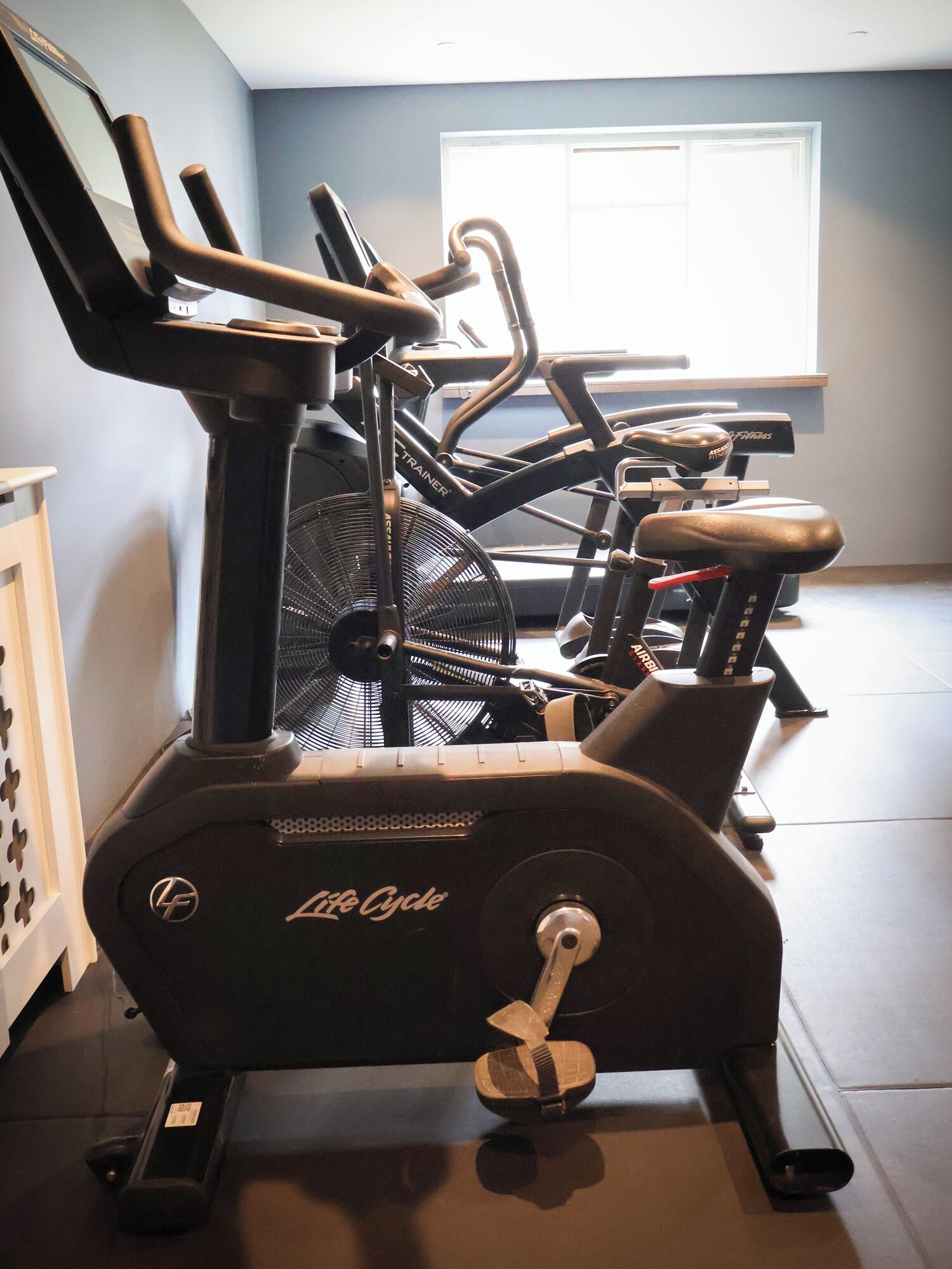 Un v élo d’appartement, un tapis de course et une fenêtre dans une pièce.