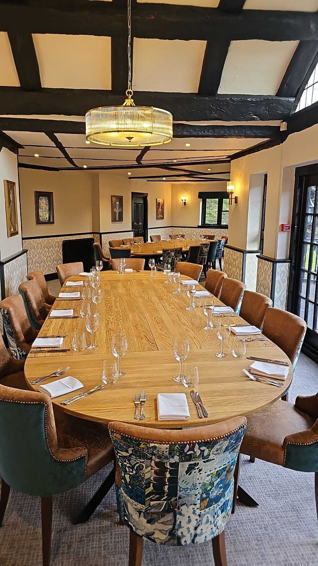 A large conference room with a long wooden table set for a meeting, surrounded by upholstered chairs.