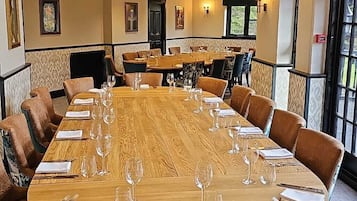A large conference room with a long wooden table set for a meeting, surrounded by upholstered chairs.