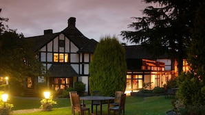 Un edificio de estilo Tudor tradicional con un jardín bien cuidado y un área de estar al aire libre.
