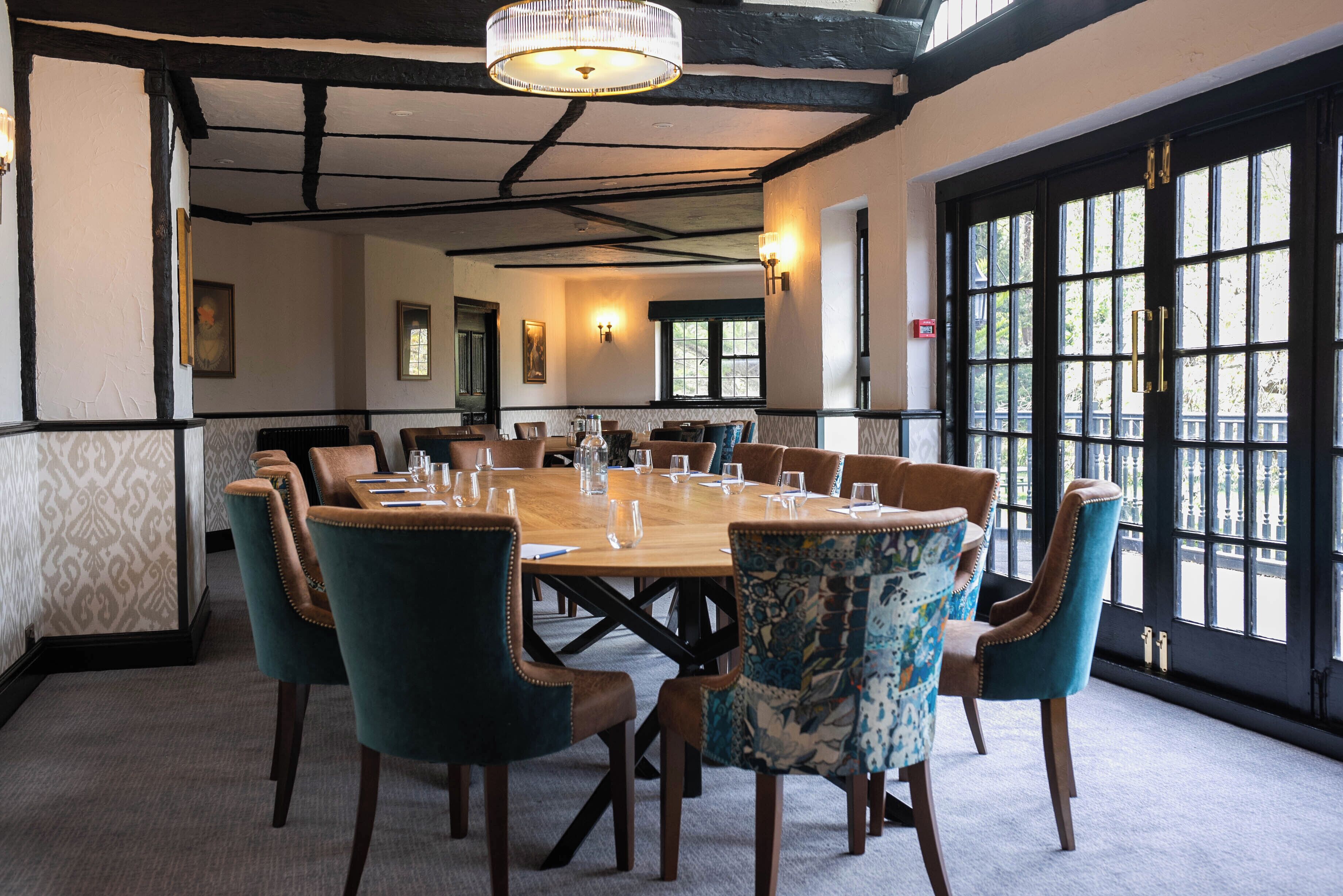 A dining room with a large wooden table set for a meal, surrounded by upholstered chairs.