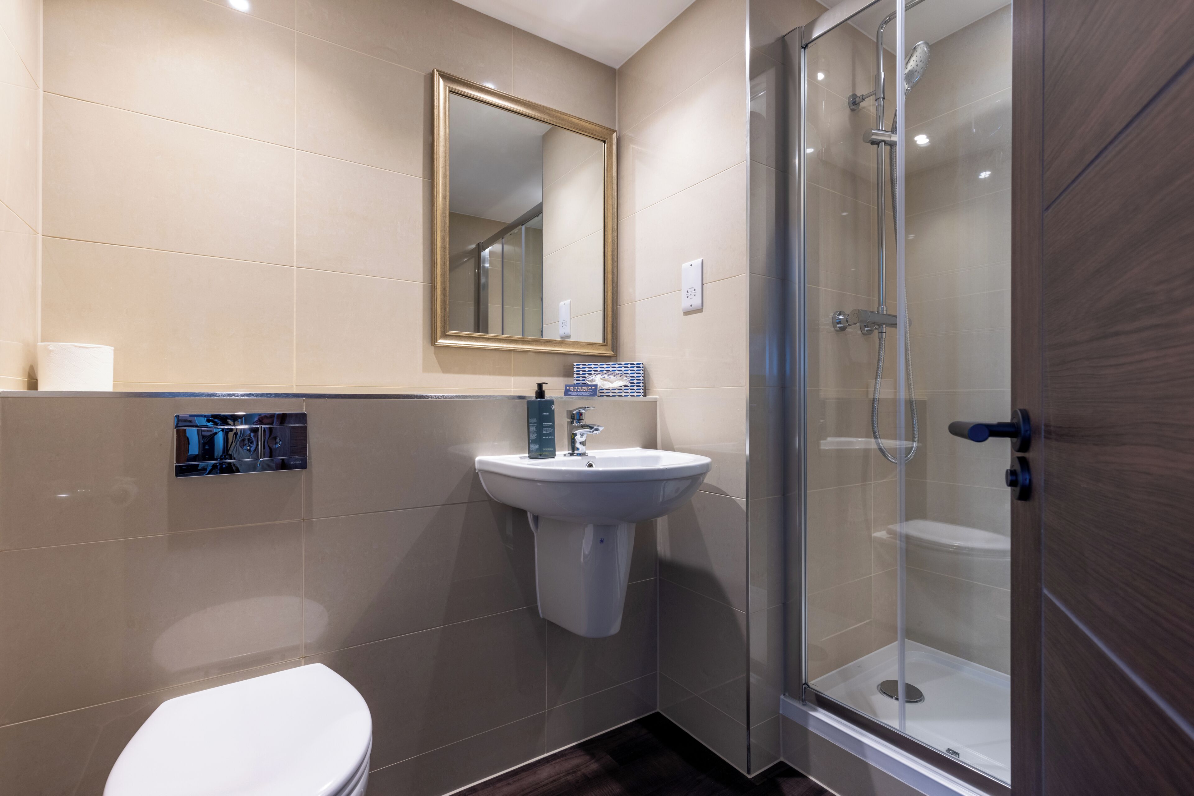 Ein Badezimmer mit Toilette, Waschbecken, Spiegel und Duschkabine.