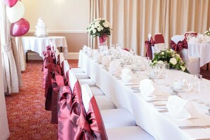 A banquet hall with long tables set for a formal event, featuring white tablecloths, silverware, and glassware. - Holiday Inn Ipswich Orwell by IHG (Ipswich)