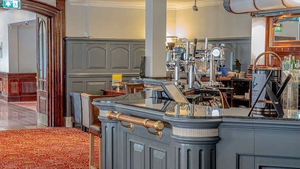 A bar area with a counter, bar stools, and a coffee machine. - Holiday Inn Ipswich Orwell by IHG (Ipswich)