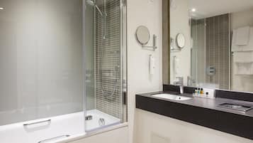Un baño moderno con ducha envuelta en vidrio, una bañera blanca, encimera negra y un espejo grande.