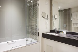 Un baño moderno con ducha envuelta en vidrio, una bañera blanca, encimera negra y un espejo grande.