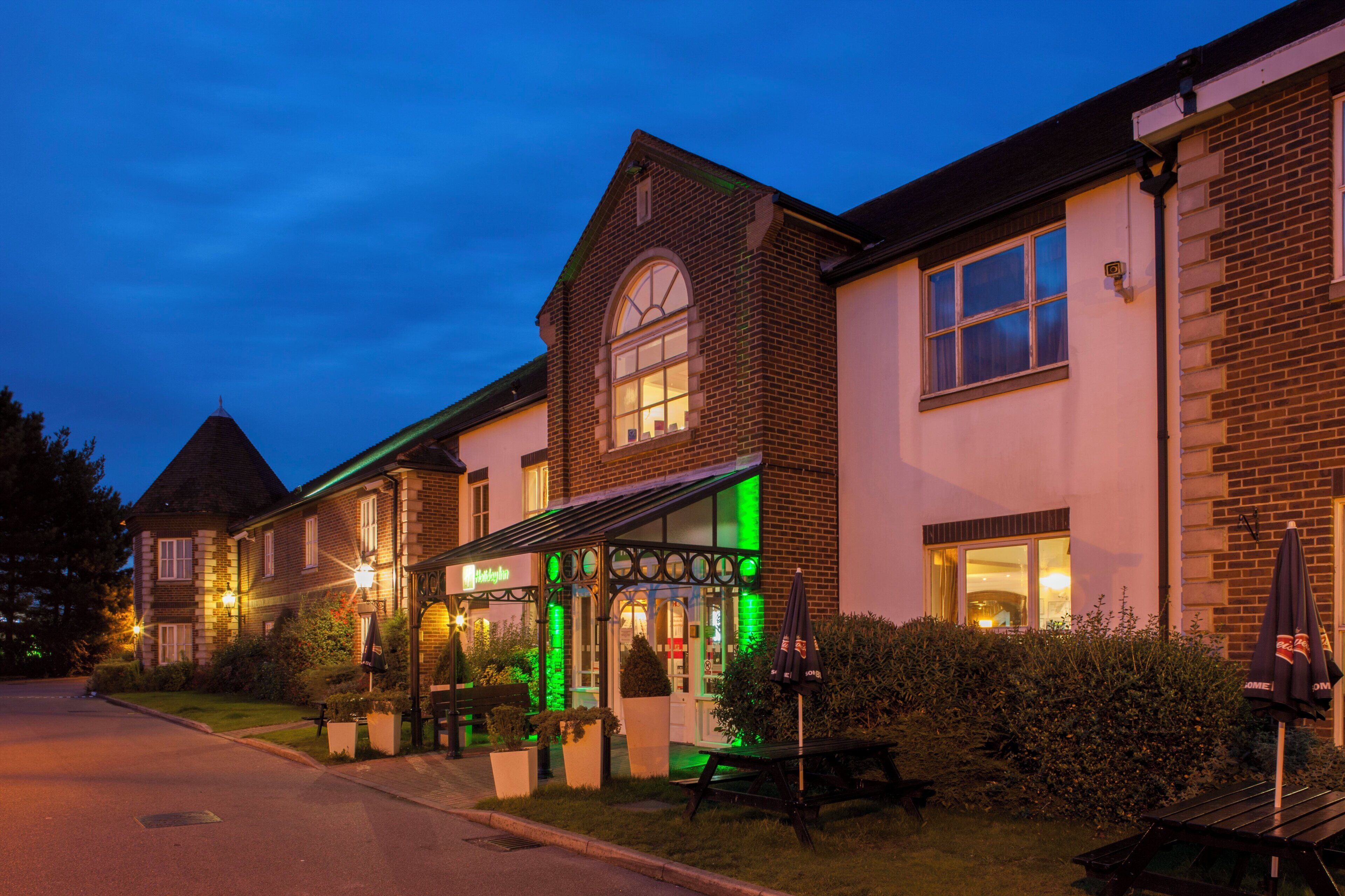 A hotel with a traditional brick facade, a covered outdoor seating area, and a well-lit entrance.