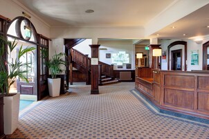 Un vestíbulo de hotel con una imponente escalera, una recepción y un letrero de Holiday Inn.