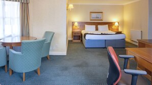 A hotel room with a bed, desk, chairs, and a dining table. - Holiday Inn Ipswich Orwell by IHG (Ipswich)