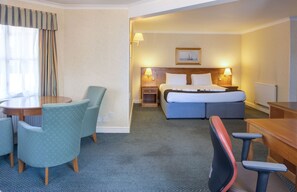 A hotel room with a bed, desk, chairs, and a dining table. - Holiday Inn Ipswich Orwell by IHG (Ipswich)