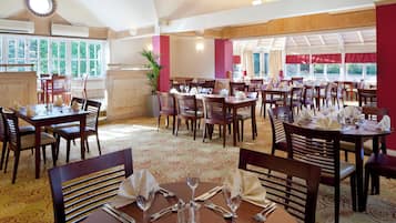 A spacious dining area with multiple tables and chairs, large windows, and a high ceiling with a skylight.