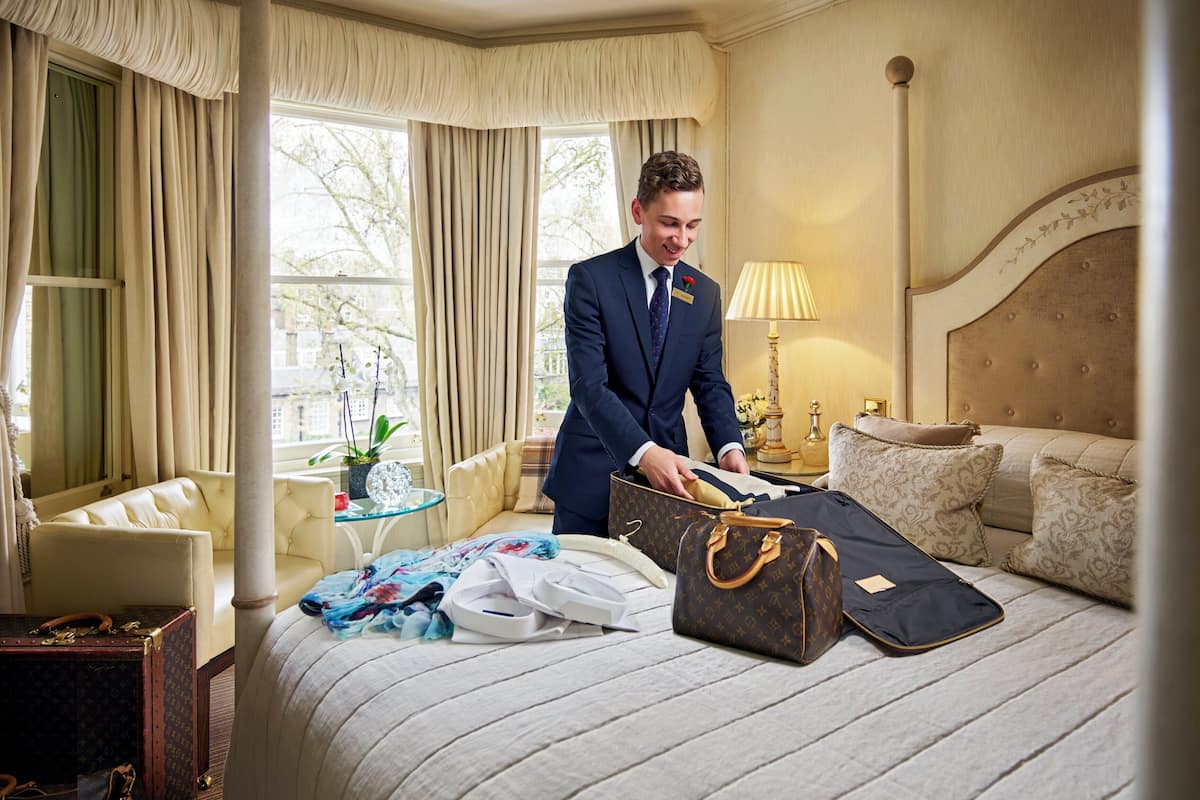 A well-appointed hotel room with a large bed, a sitting area with a chair and a table, and a window with curtains.