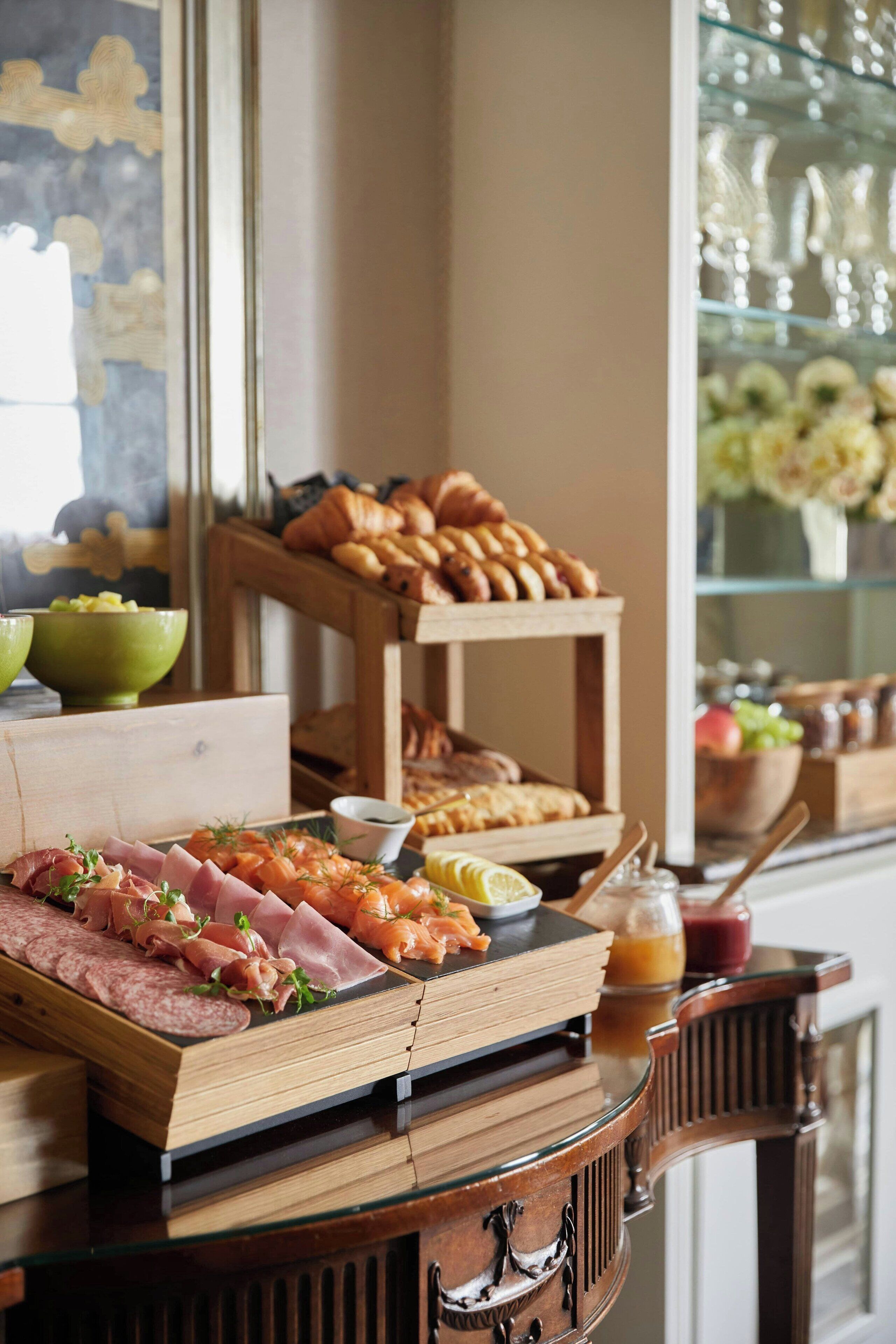 A buffet with various food items including meats, pastries, and fruits.