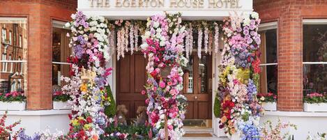 The Egerton House Hotel entrance with a large wooden door and a floral archway.