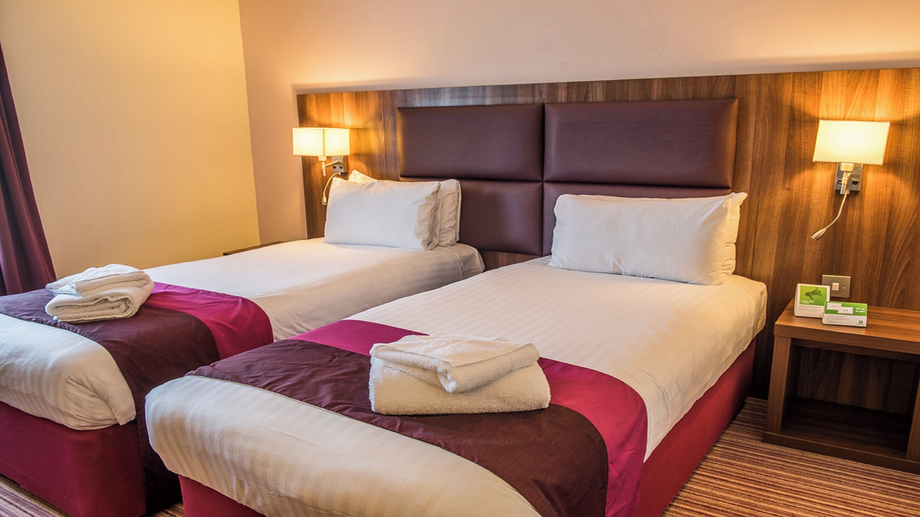 Une chambre d’hôtel avec deux lits, chacun doté d’une tête de lit, de lampes de chevet et de serviettes.