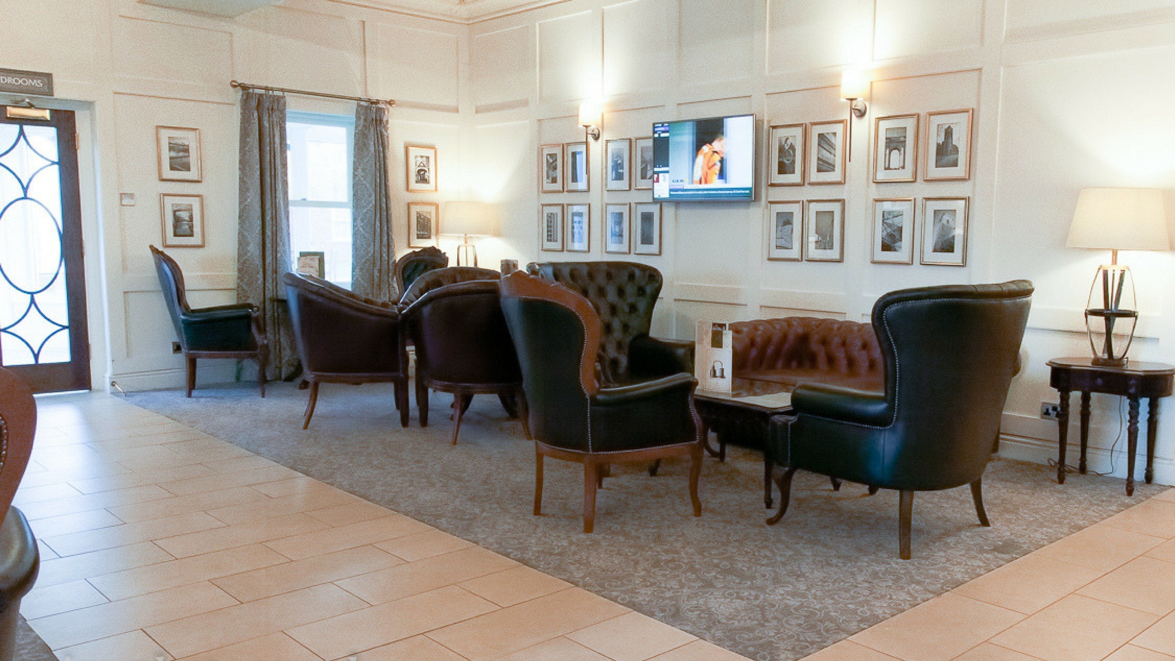 A room with a television, framed pictures, and a variety of seating options.