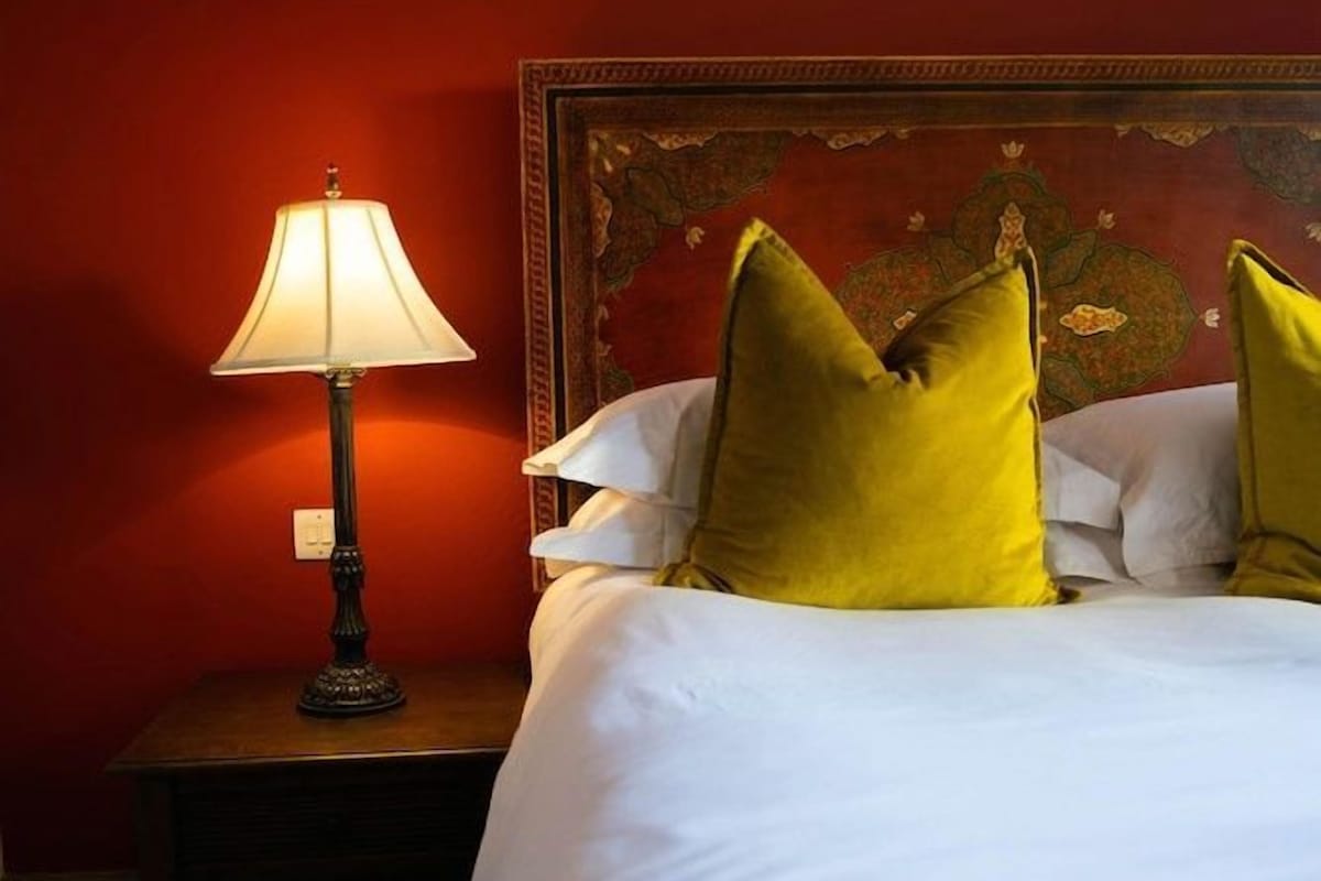 A hotel room with a bed, a nightstand, and a lamp.