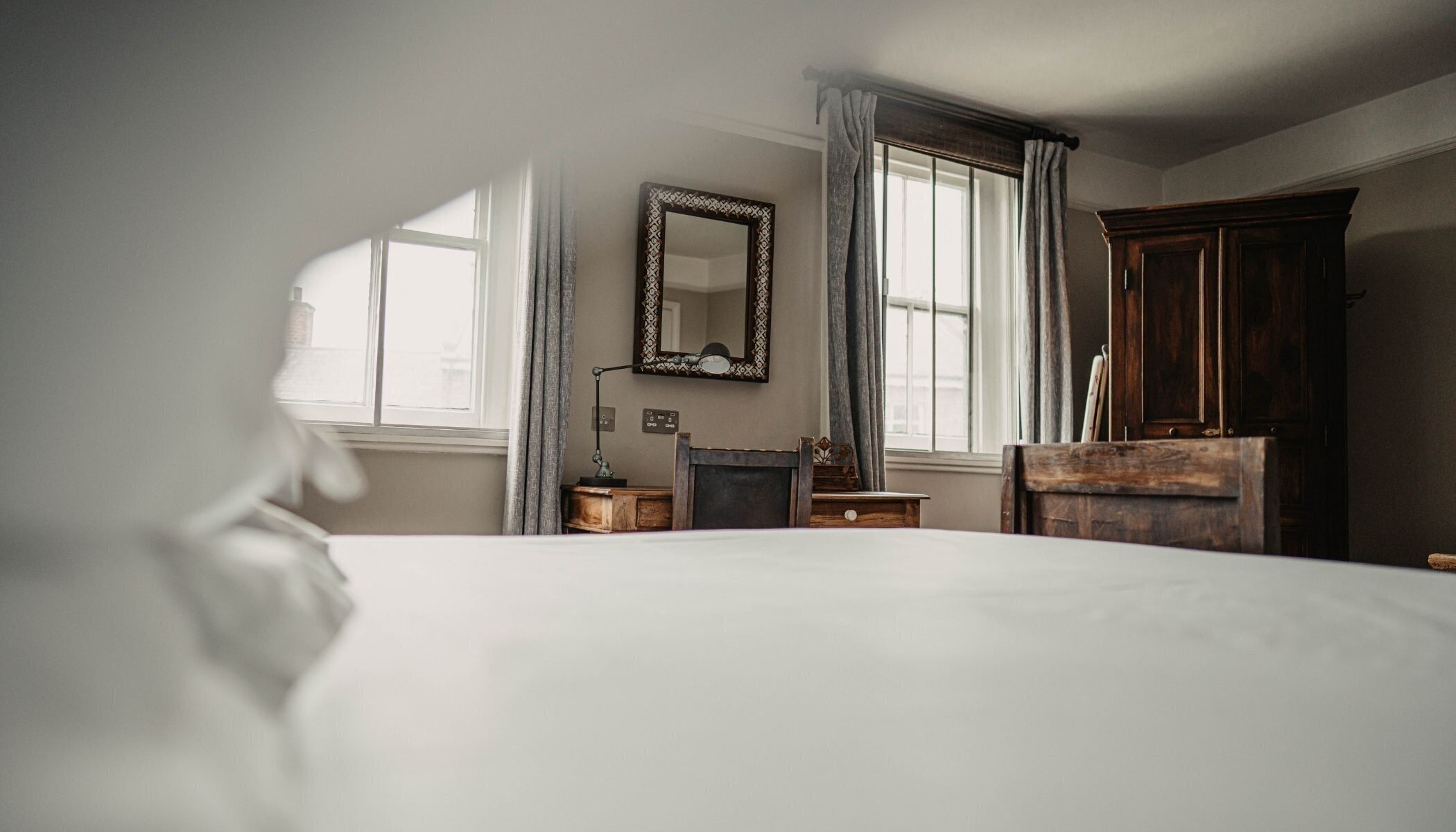 A bedroom with a large bed, a wooden dresser, a mirror, and a desk.