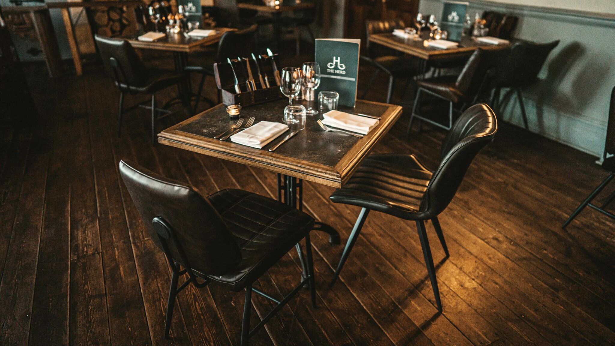 Un restaurante con mesas de madera y sillas de cuero negro.