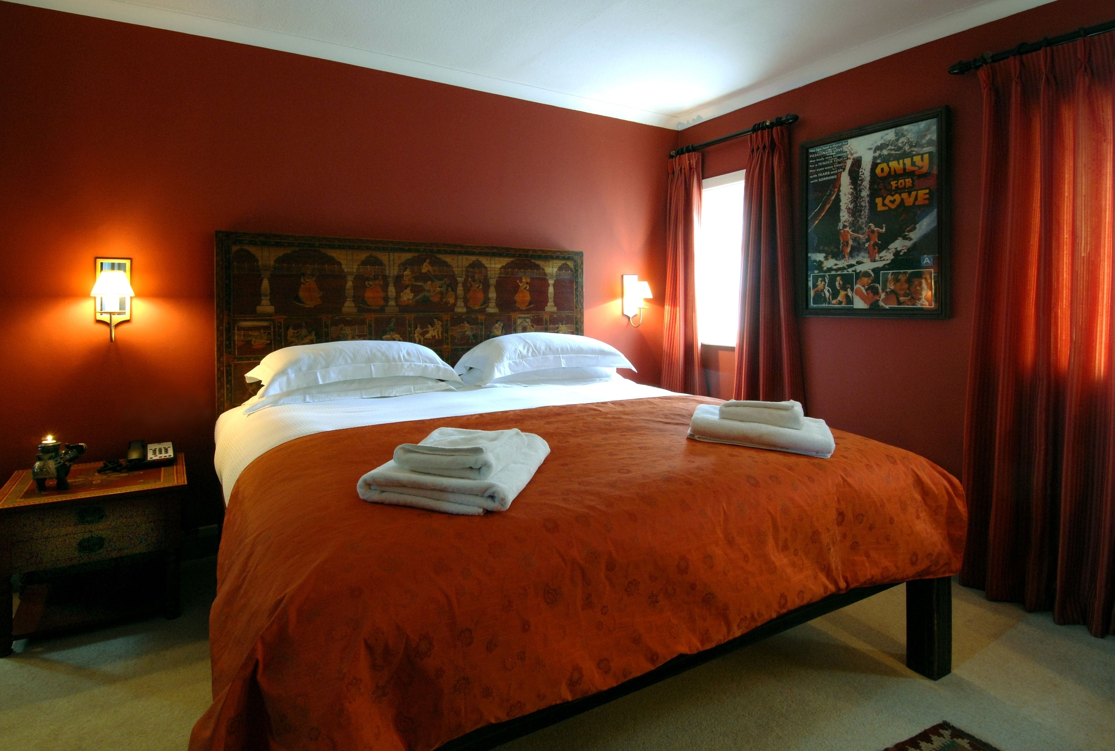 Una habitación de hotel con una cama grande, dos mesitas de noche y un cartel en la pared.
