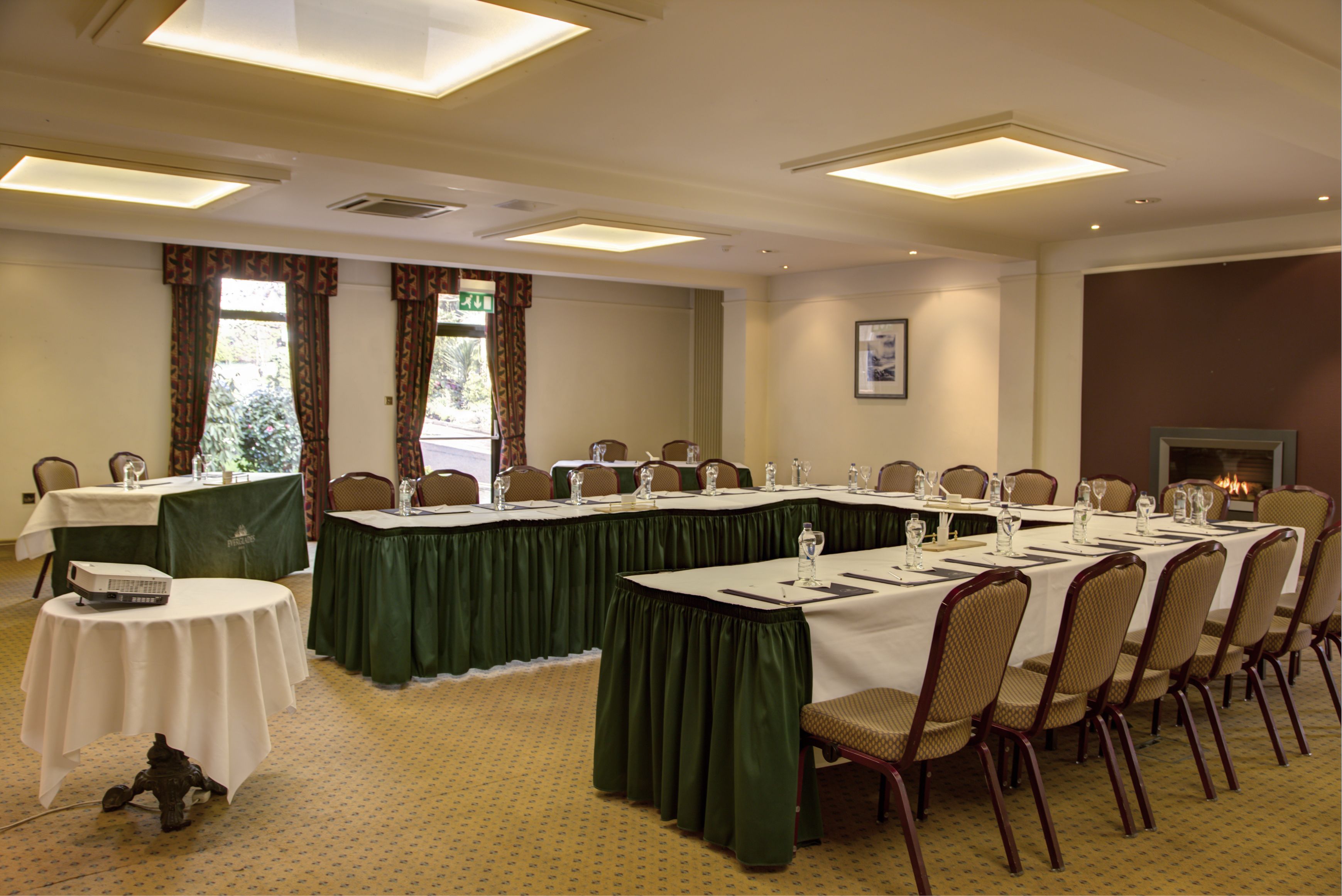 A conference room with long tables, chairs, and a fireplace.