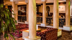 A bar area with marble columns, patterned sofas, and a bar counter. - Everglades Hotel (Londonderry)
