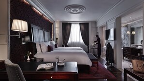 Ein Hotelzimmer mit einem großen Bett, Nachttischen, einem Schreibtisch mit Stuhl, einem Fernseher und einem durch eine offene Tür einsehbarer Badezimmer.