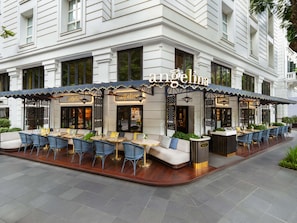 An exterior of a restaurant with outdoor seating, a covered patio area, and a sign reading 'angelina'. - Sofitel Legend Metropole Hanoi (Hanoi)