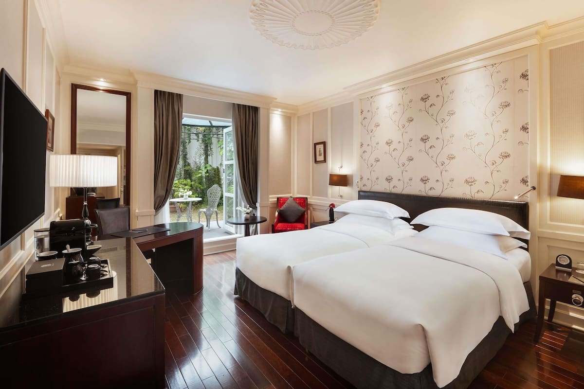 A hotel room with a bed, a desk, a TV, and a view of the outdoors.