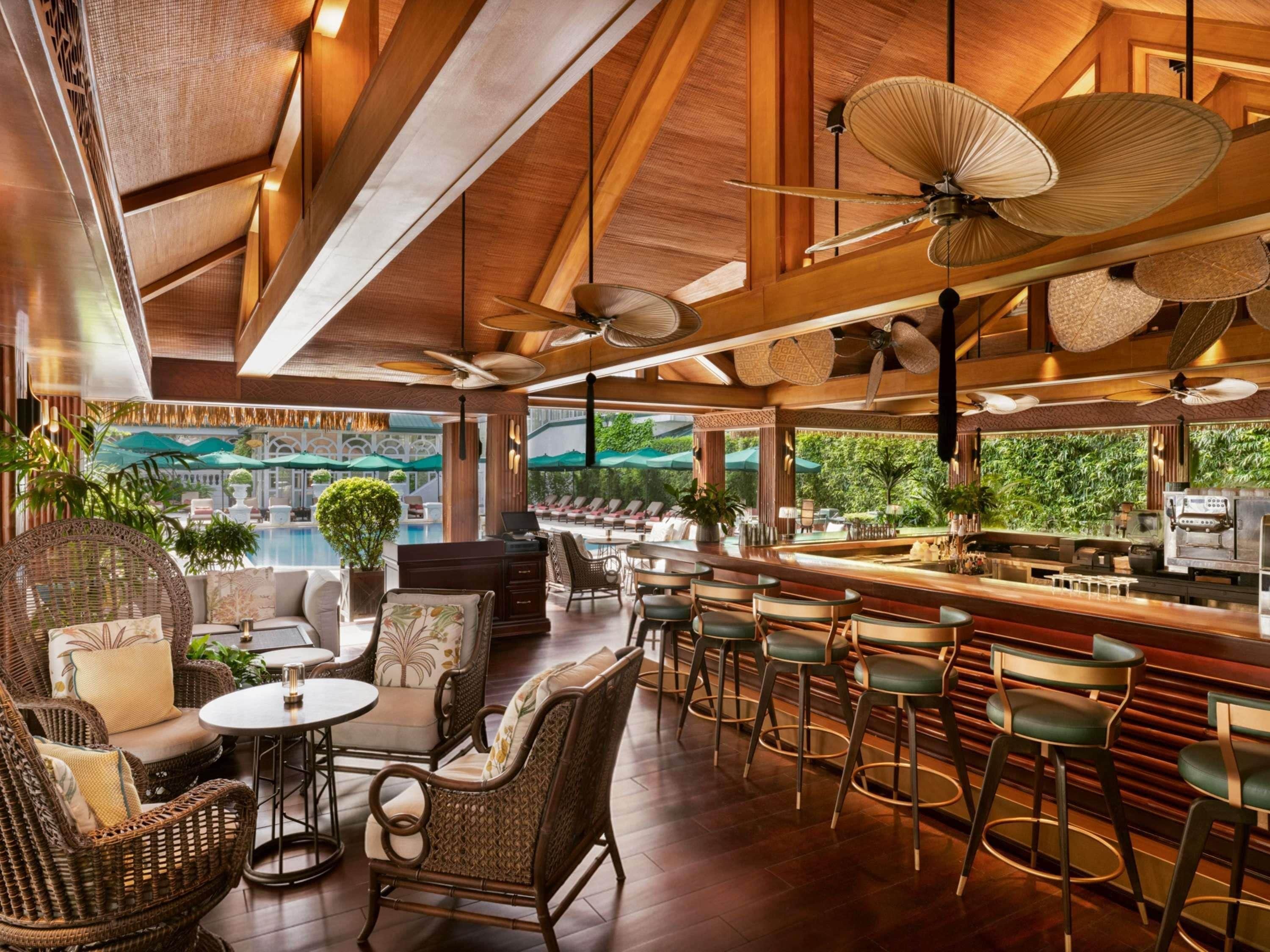 Eine Bar mit Korbmöbeln, Blick auf den Pool und Deckenventilatoren.
