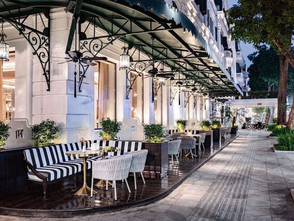 An outdoor cafe with striped seating, hanging lanterns, and a covered walkway.