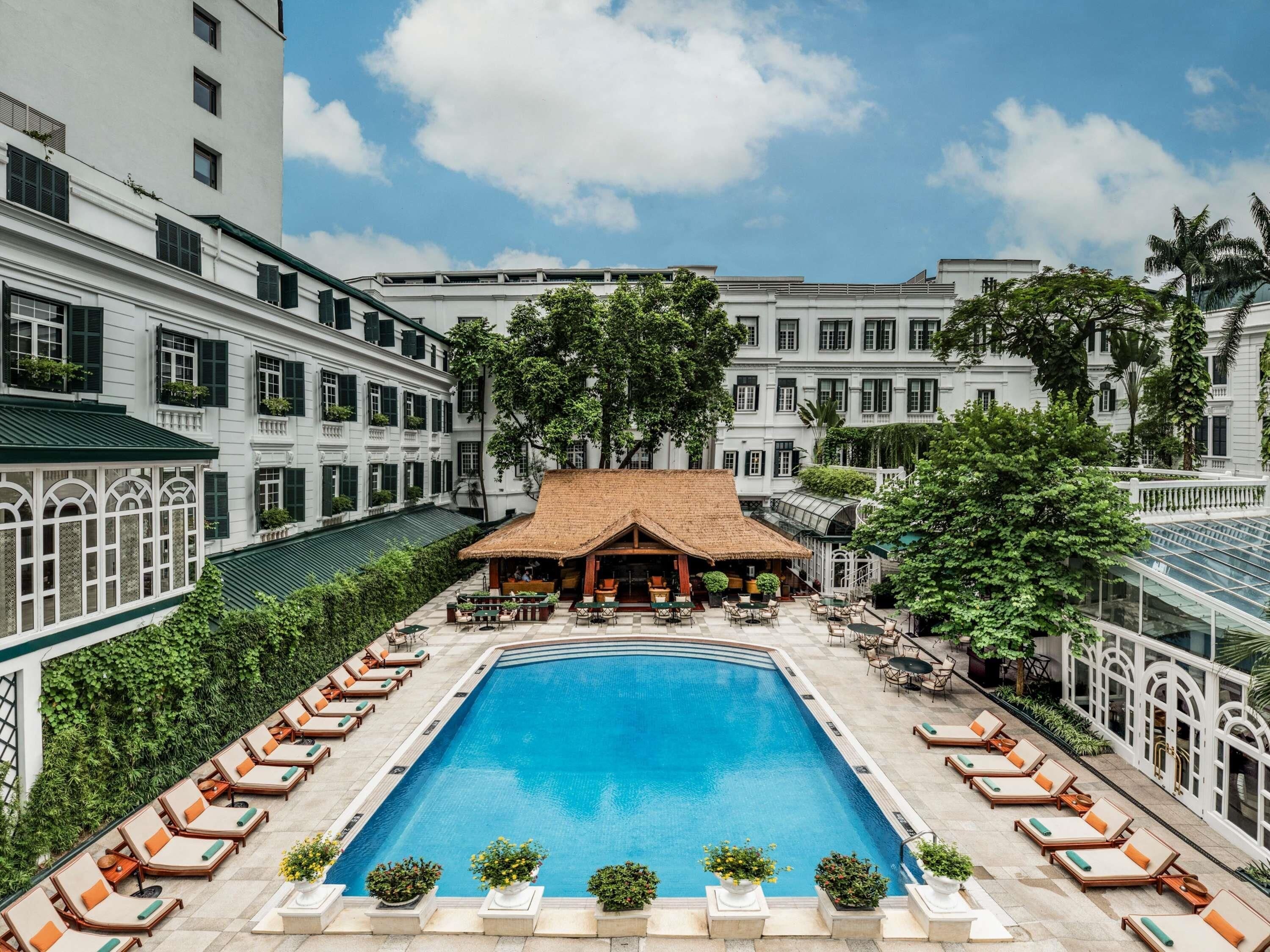 A swimming pool surrounded by lounge chairs and a building with multiple windows.
