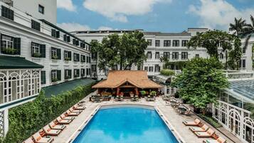 A swimming pool surrounded by lounge chairs and a building with multiple windows.