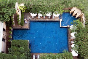 A large rectangular pool with a stone border, surrounded by white umbrellas and potted plants. - The Great Duke Phnom Penh (Phnom Penh)
