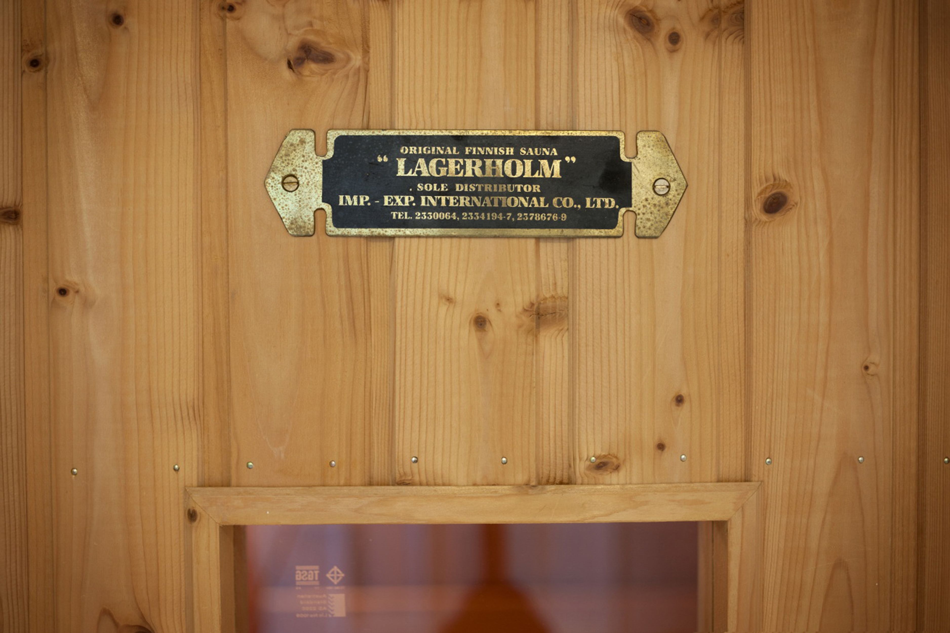 A wooden wall with a metal plaque that reads "Original Finnish Sauna Lagerholm Sole Distributor."