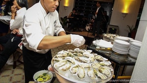 A chef serving oysters in a restaurant setting with tables and other diners in the background. - The Great Duke Phnom Penh (Phnom Penh)