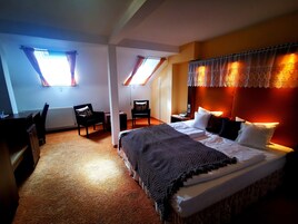 Una habitación de hotel con una cama, dos sillas, un escritorio y un radiador.