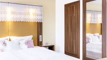A hotel room with a large bed, a wooden wardrobe, a nightstand, and a mirror.