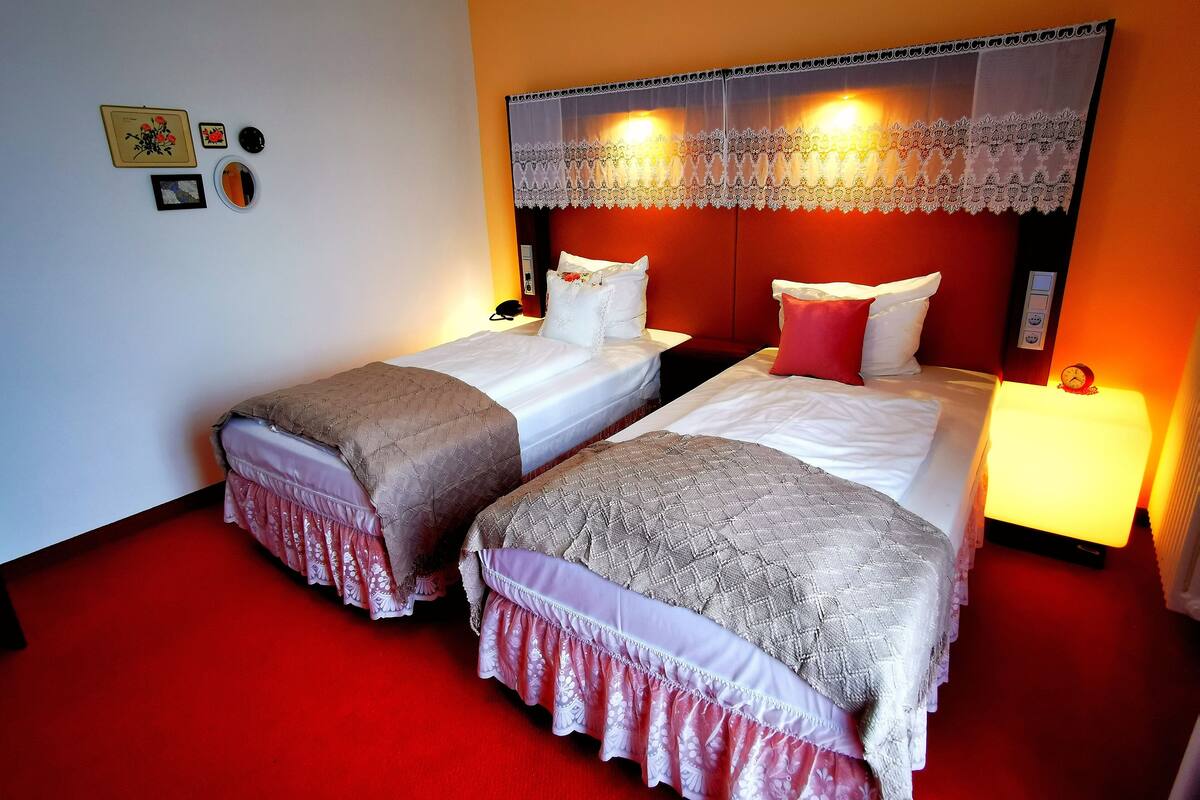 A hotel room with two beds, red carpet, and a decorative headboard.