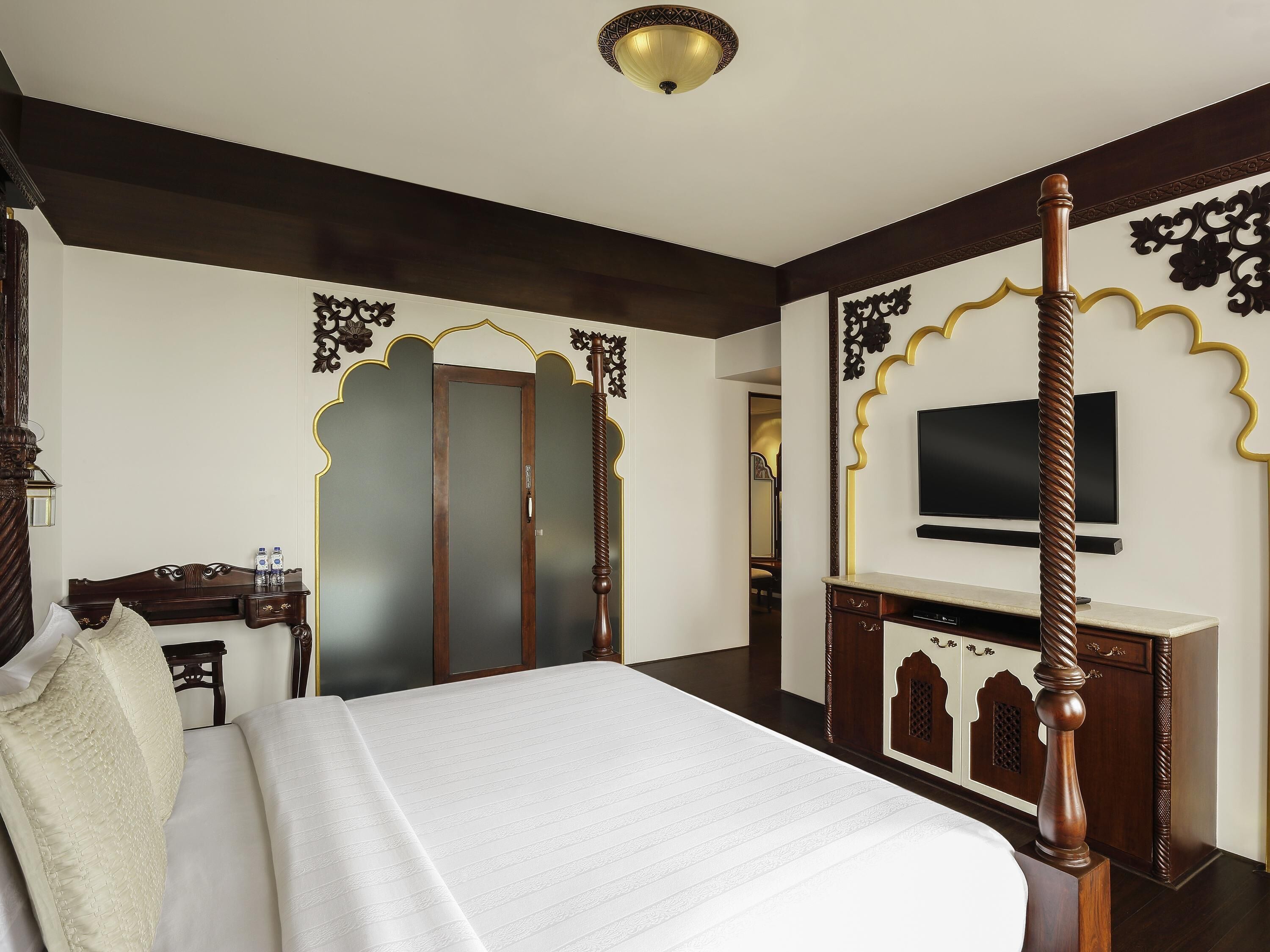 Ein Bett mit Baldachin, ein an der Wand befestigter Fernseher und ein Schreibtisch mit Stuhl.