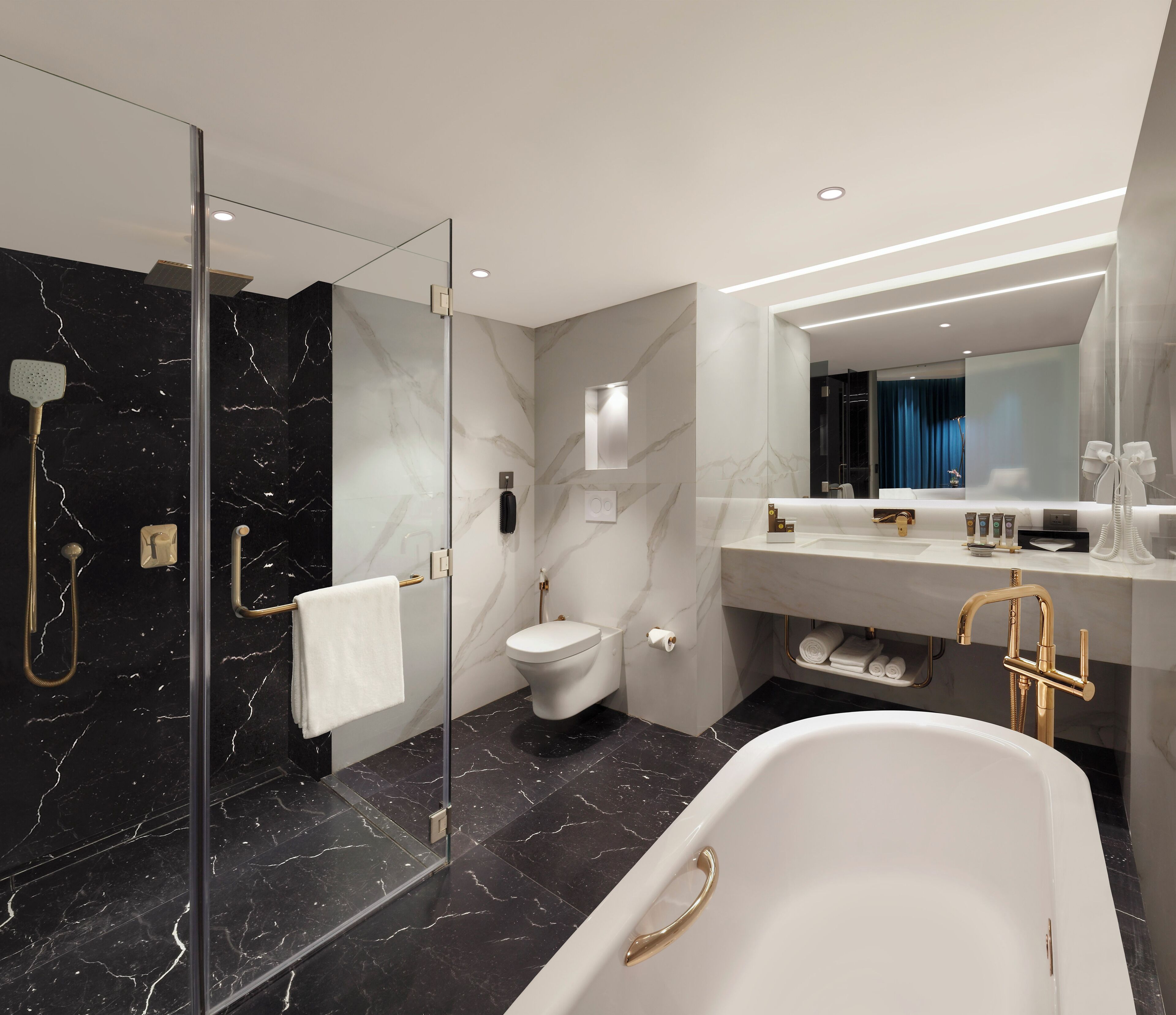 Un baño moderno con ducha envuelta en vidrio, una bañera blanca y un tocador con espejo.
