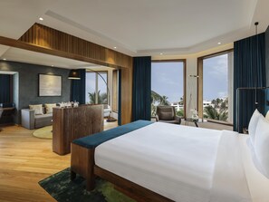 Ein modernes Hotelzimmer mit einem großen Bett, einem Schreibtisch, einem Sessel und Blick auf die Stadt.