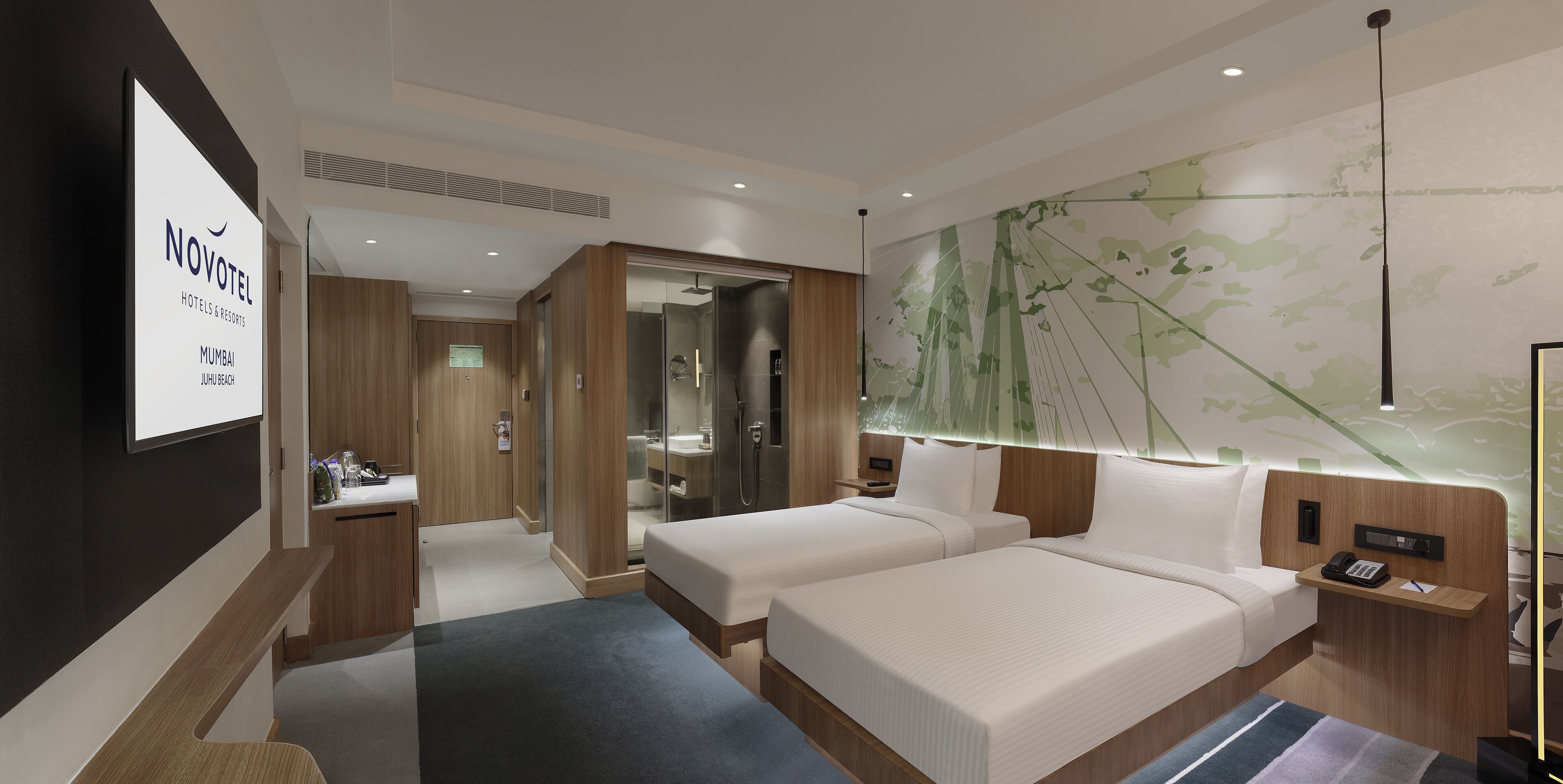 A modern hotel room with two beds, a shower area, and a large wall mural.