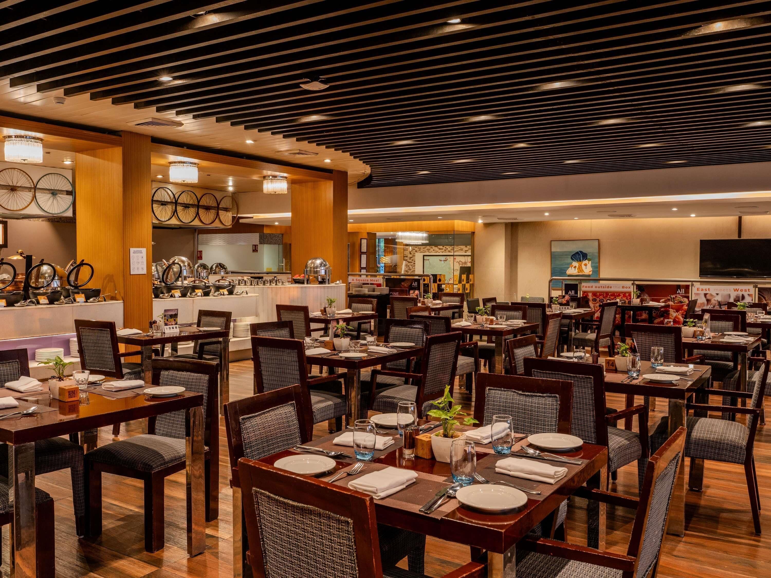 Un restaurant doté de plusieurs tables et chaises, d’un espace buffet et d’une cuisine située à l’arrière.