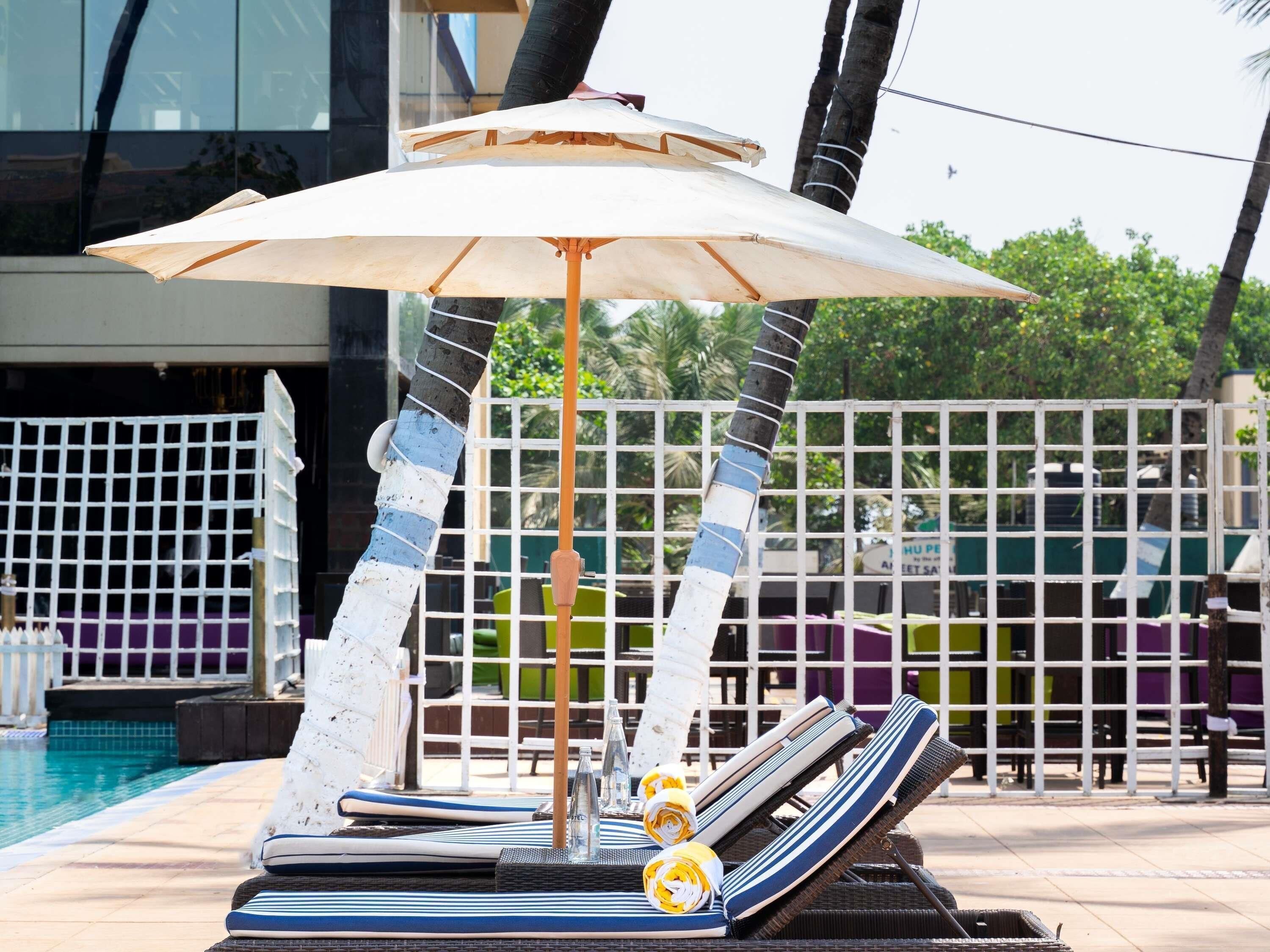 Un espace aménagé au bord de la piscine, avec des chaises longues, un parasol et une piscine.