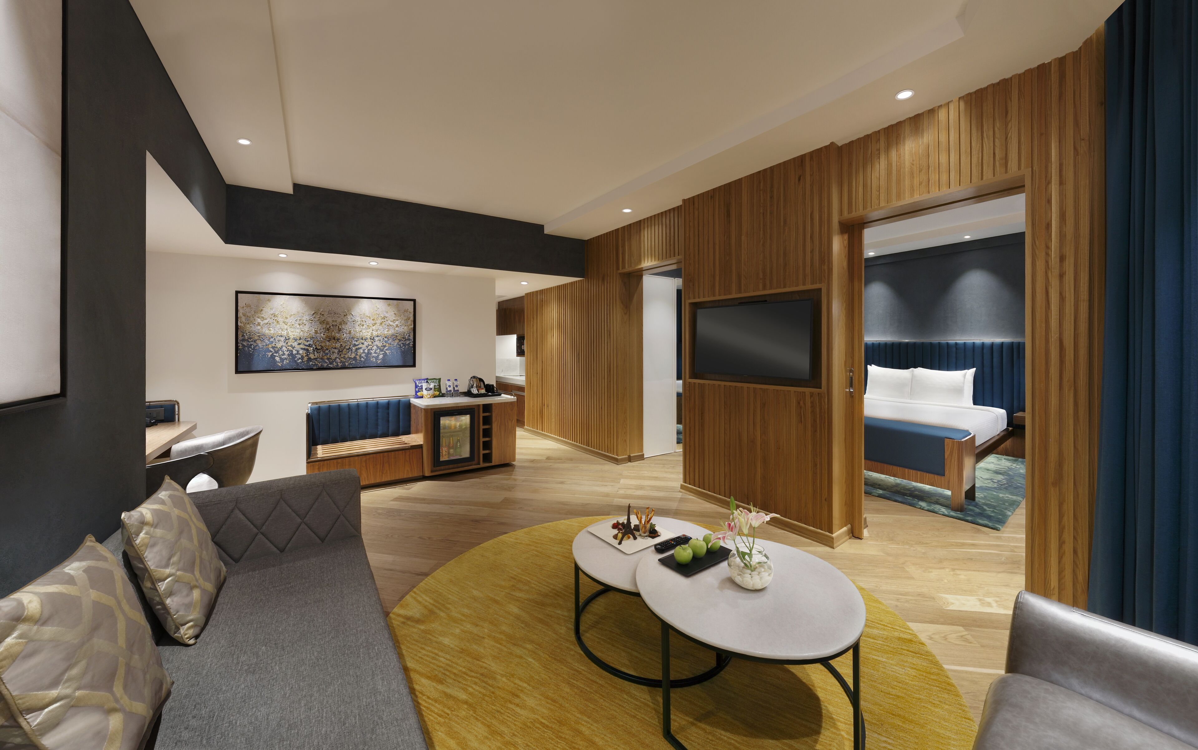 Une chambre d’hôtel moderne avec un canapé, une table basse ronde, un téléviseur et un lit donnant sur une vue agréable.