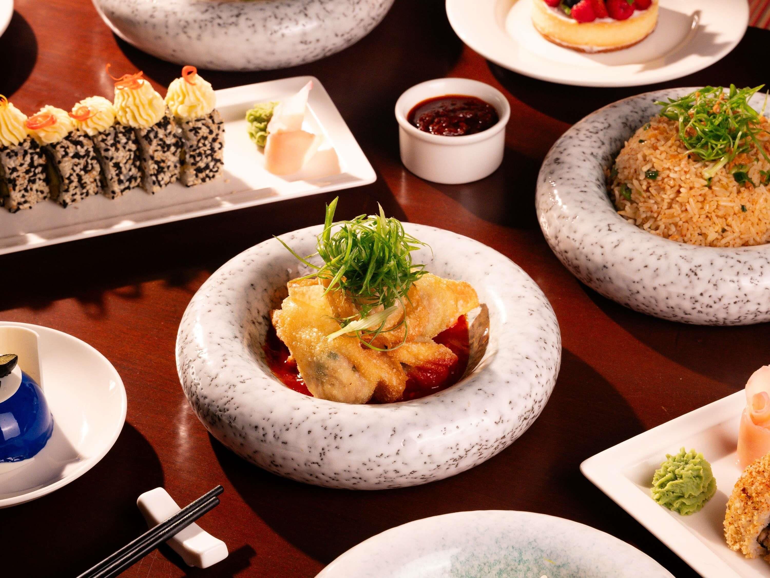 Variedad de platillos en una mesa, como sushi, arroz y un postre.