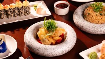 Variedad de platillos en una mesa, como sushi, arroz y un postre.