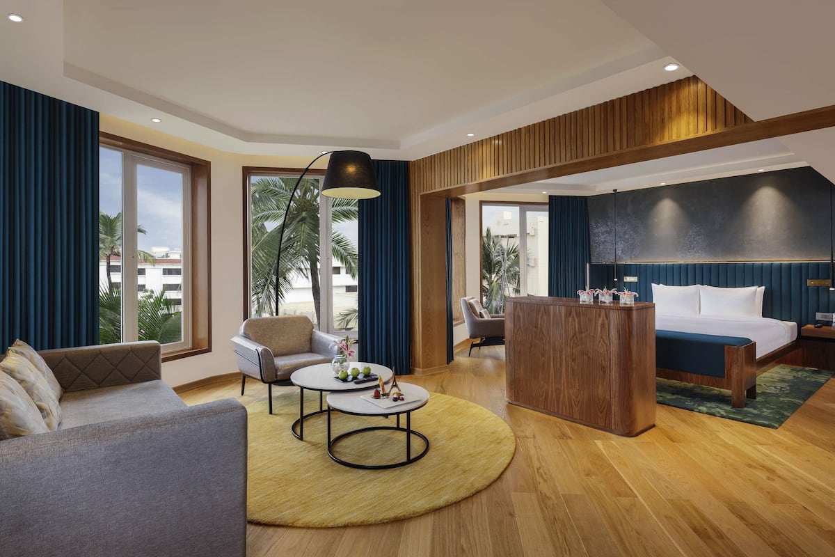 Habitació d'hotel moderna amb llit, sofà, butaca i una taula de cafè petita.